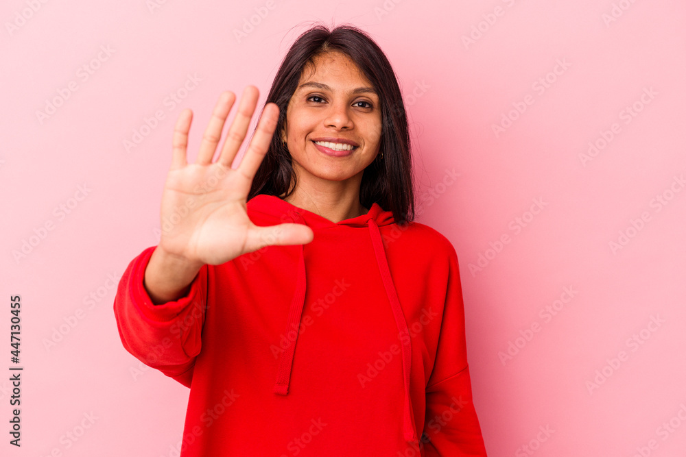 Young latin woman isolated on pink background smiling cheerful showing number five with fingers. Young latin woman isolated on pink background smiling cheerful showing number five with fingers.