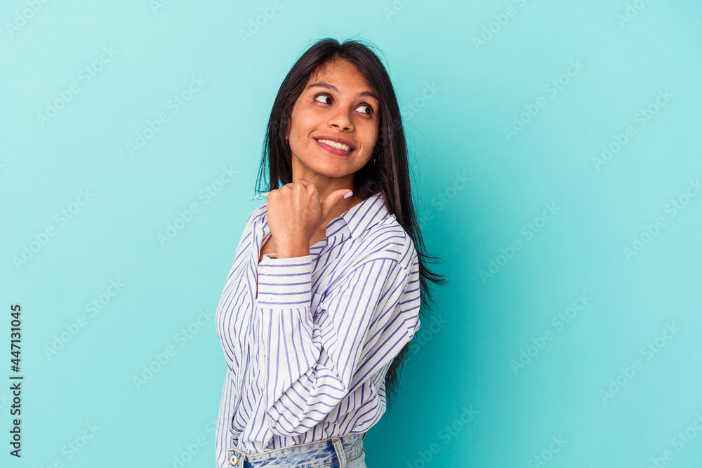 Fototapeta premium Young latin woman isolated on blue background points with thumb finger away, laughing and carefree.