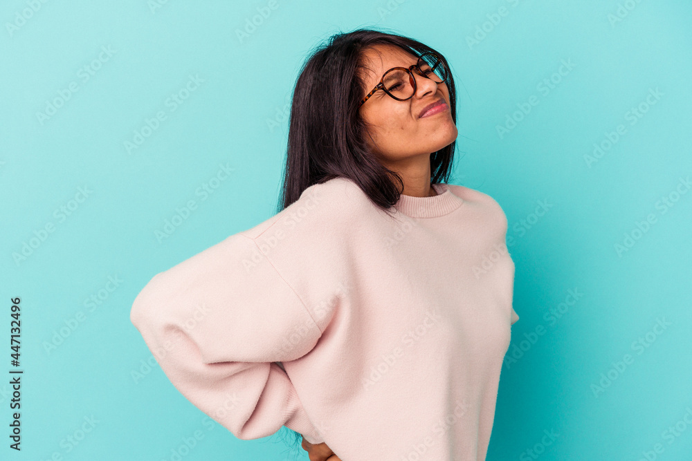 Young latin woman isolated on blue background suffering a back pain.