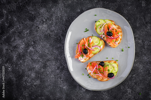 Toasts with cream cheese, smoked salmon, cucumber, black olives and red onion. Open sandwiches. Healthy care, super food concept. Top view, overhead