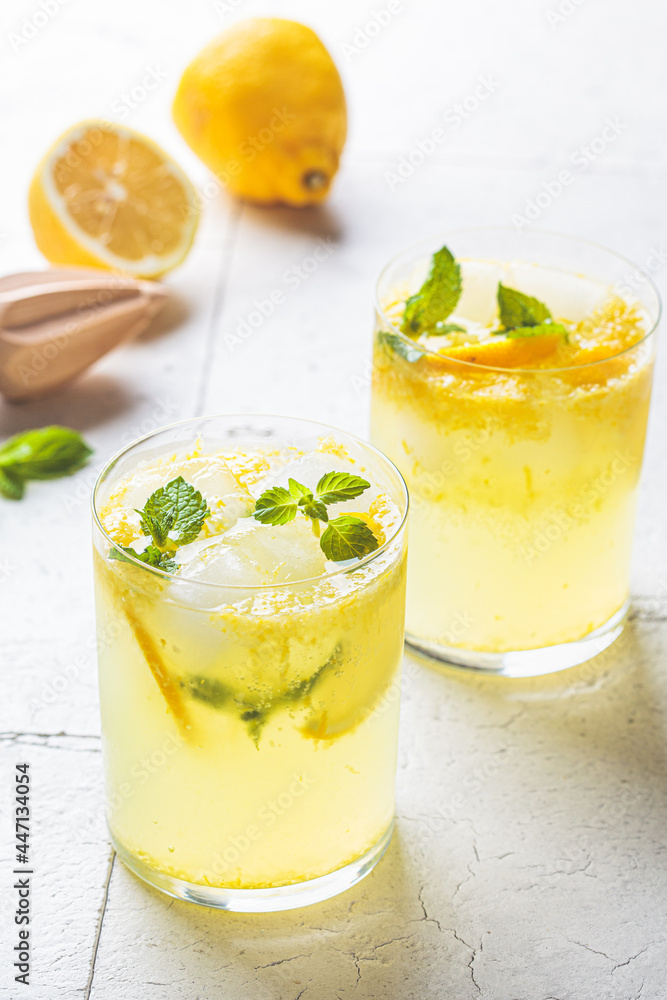 Homemade lemonade with mint and ice in glasses, gray tiles background. Homemade lemonade with mint and ice in glasses, gray tiles background.