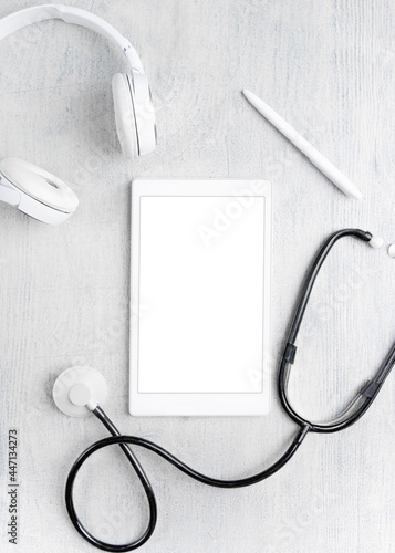 On a gray background, a tablet with a stethoscope and headphones. Online Medicine concept