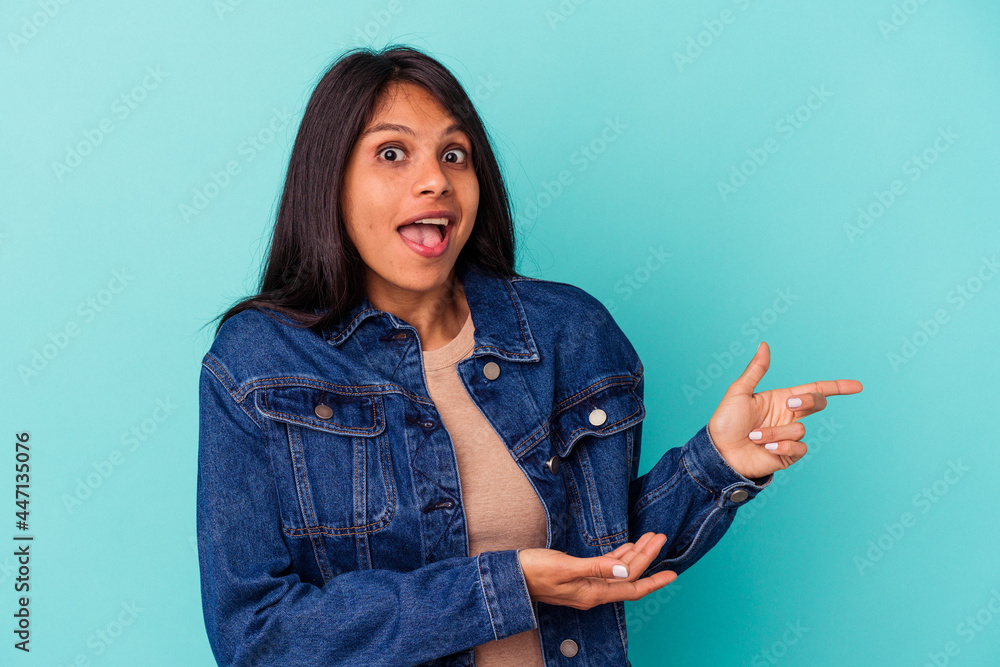 Young latin woman isolated on blue background excited pointing with forefingers away. Young latin woman isolated on blue background excited pointing with forefingers away.