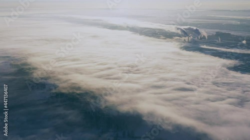 Town Skyline And Of Old Factory Pipes. Bird's-eye View At Sunny Snowy Winter Day 4K. Plant Pipe With Escaping Steam Or Smoke. Aerial View Top Elavated View Winter Snowy Landscape. Steam Light Clouds photo