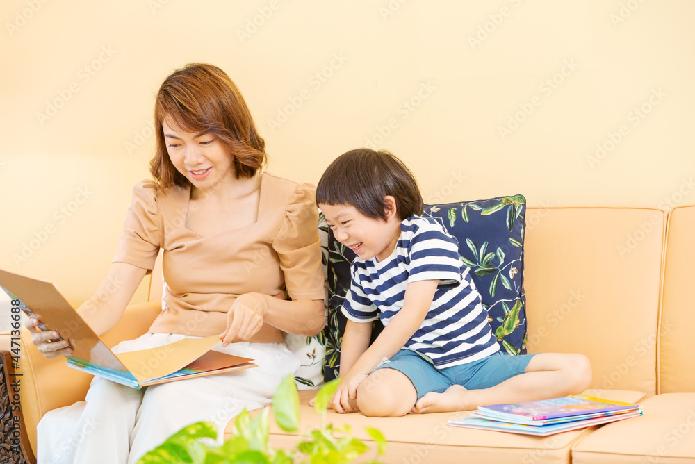 Young boy reading book and studies at home with his mom. Home school distance learning and happy learning online education concept Young boy reading book and studies at home with his mom. Home school distance learning and happy learning online education concept