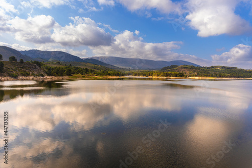 Landscape on the lake, with the cloudy sky reflected in the water. 