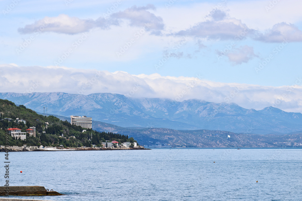 View from the sea to Alushta, Crimea. The Black Sea and blue mountains in the distance - a calm summer landscape.
