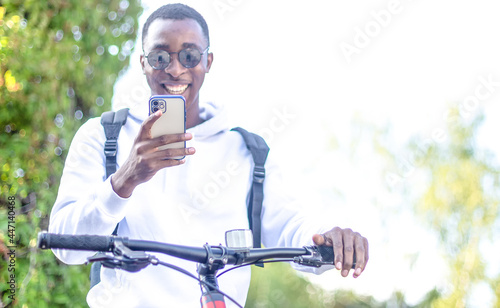 An African-American man with a phone in his hands and a bicycle