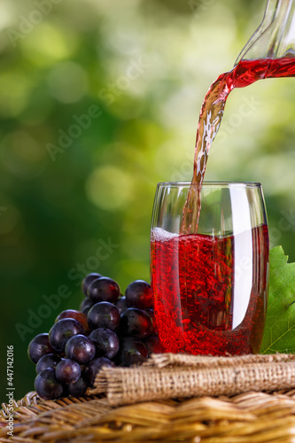 Tela grape juice pouring into glass from jug