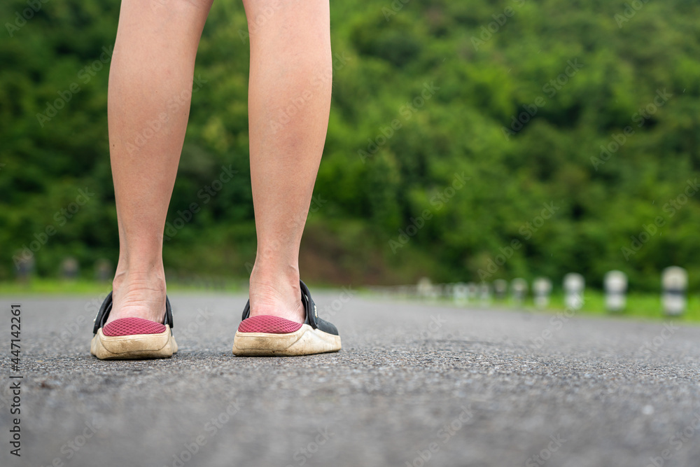 Close-up at human heel's during standing on the road with blurred background of mountain and tree. Sniffing with fresh air and relaxing activity with rural environment. Selective focus.