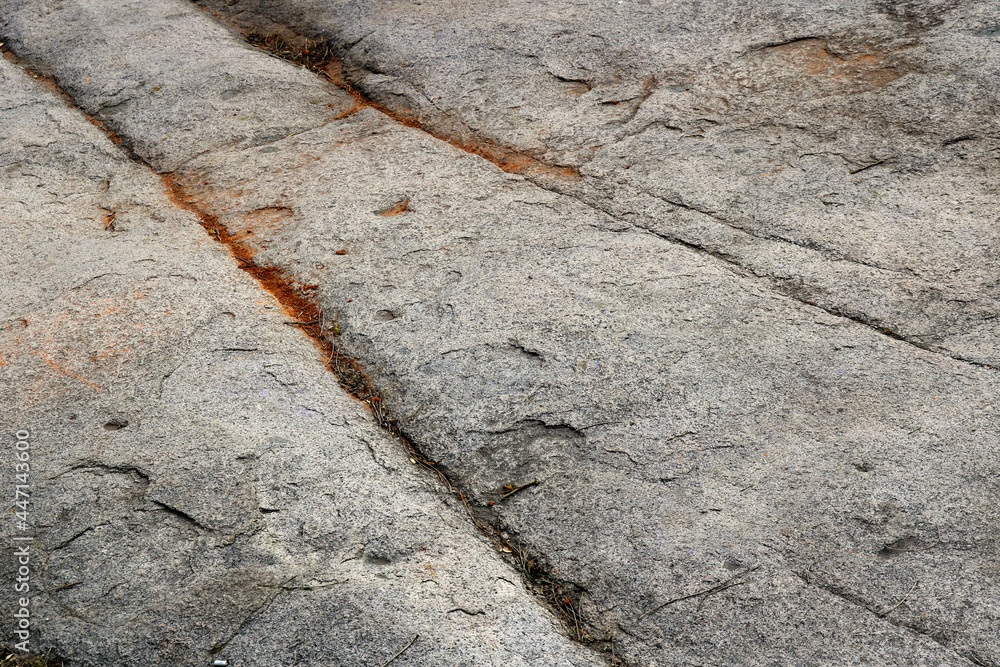 rock surface with grooves and trails carved, with some red sand rock surface with grooves and trails carved, with some red sand