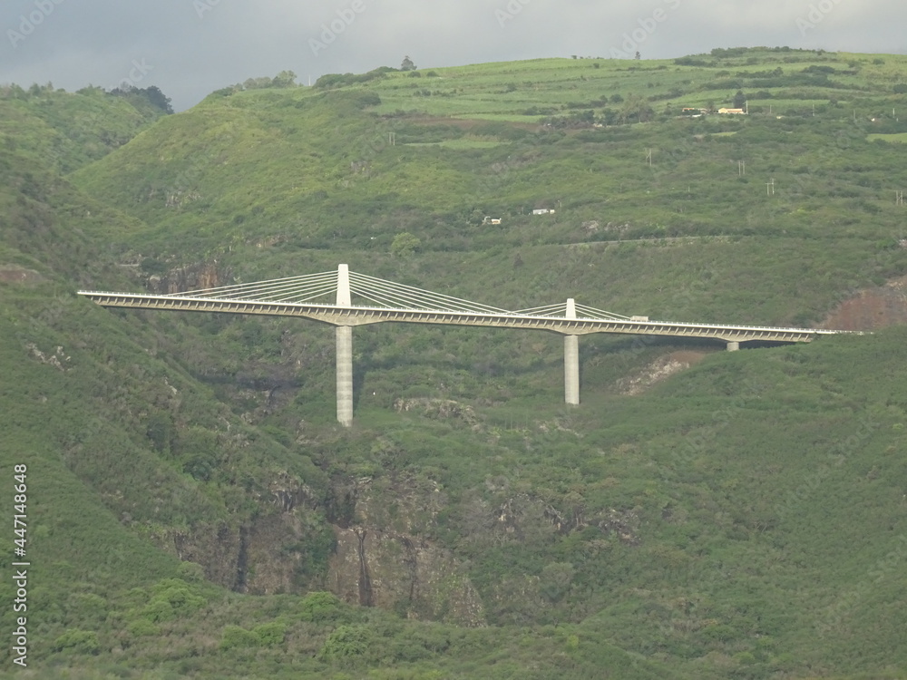 Fototapeta premium view of an unusual white metal bridge above the canyon on the tropical island of La Réunion, France