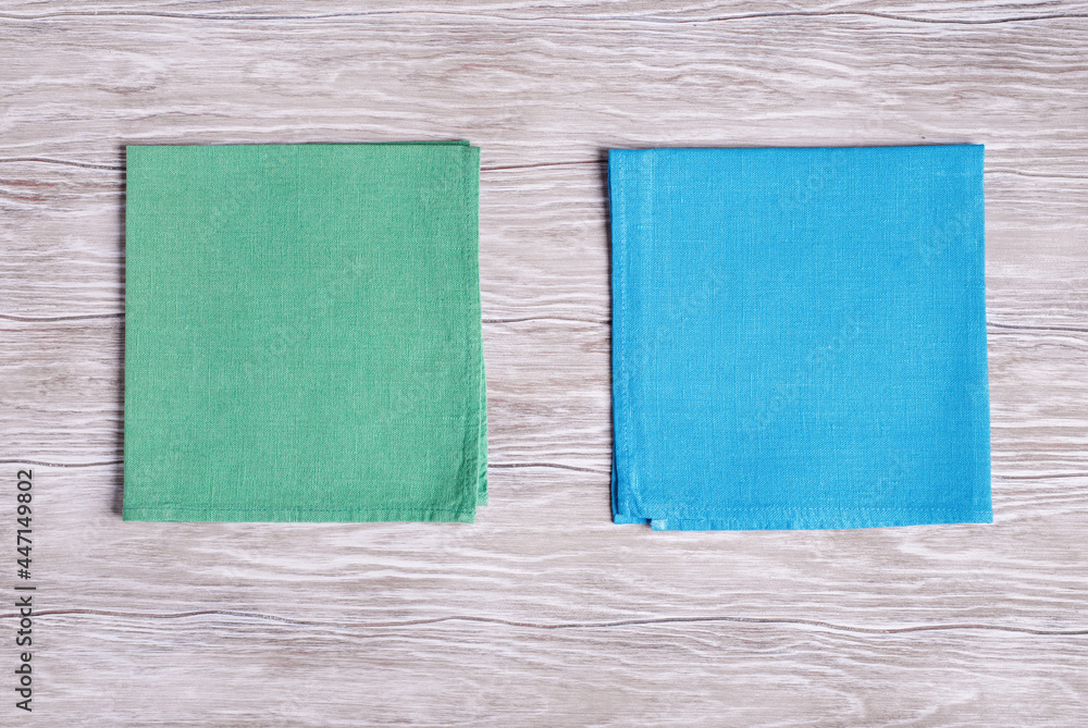 Green and blue napkins on light wooden background. Top view with copy space