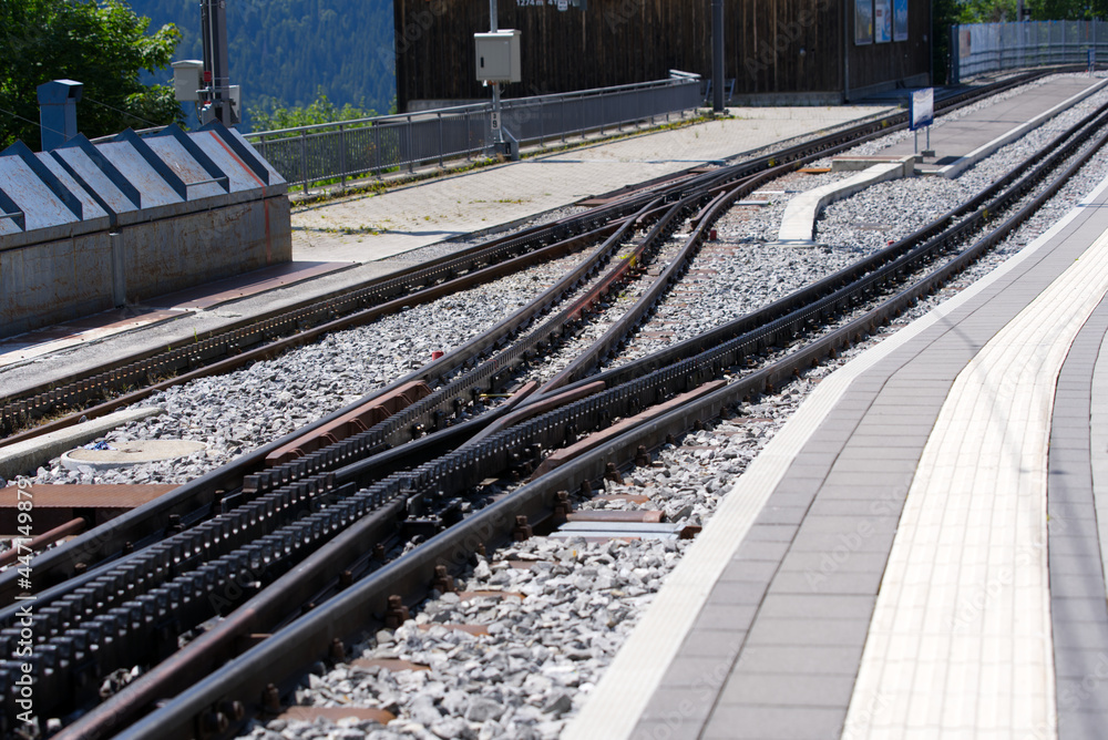 Naklejka premium Close-up of cog railway track switch at train station of Wengen on a beautiful summer day. Photo taken July 20th, 2021, Lauterbrunnen, Switzerland.