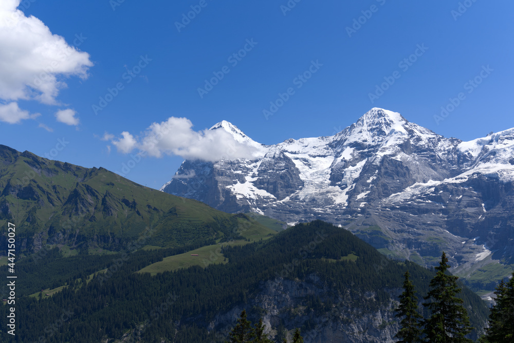 Mountain peaks Eiger and Mönch (Monk) at Bernese highland on a sunny summer day with blue sky background. Photo taken July 20th, 2021, Lauterbrunnen, Switzerland.