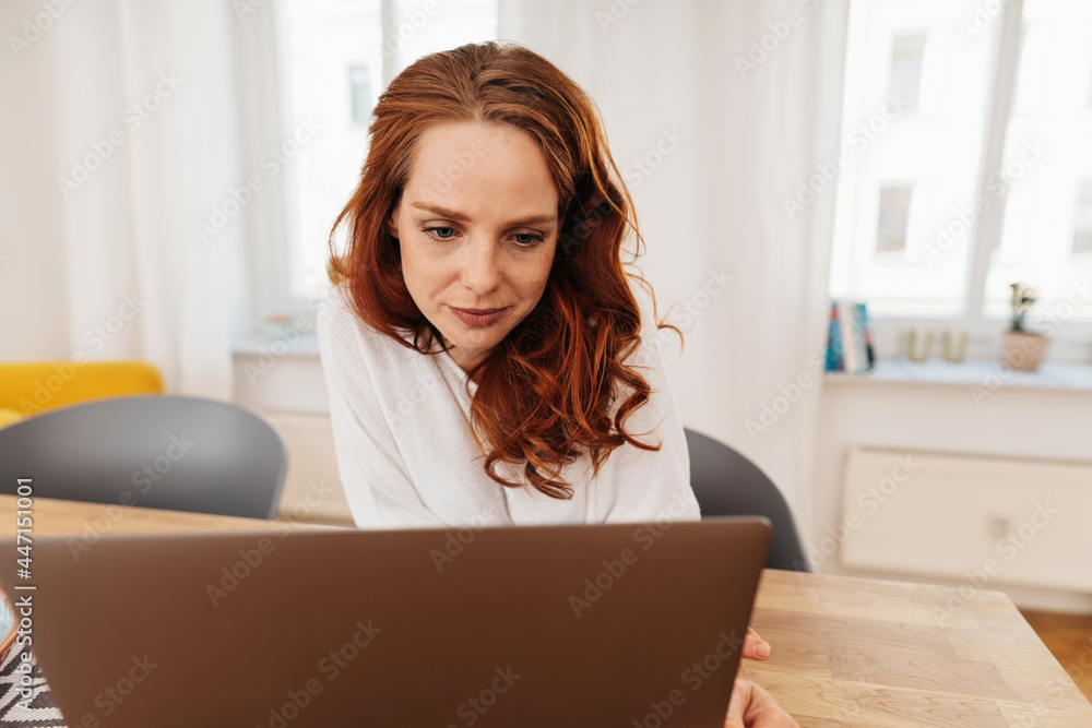 Young businesswoman smiling to herself as she works on a laptop Young businesswoman smiling to herself as she works on a laptop