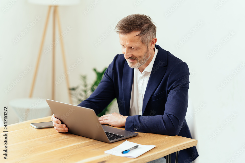 Smart businessman working on a laptop in an office Smart businessman working on a laptop in an office