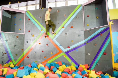 Teenage boy on climbing wall in trampoline center. Adventure and extreme for teenager concept