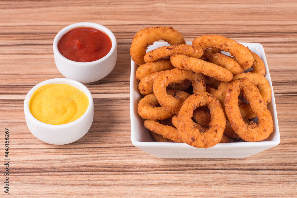 portion of onion rings on wooden background portion of onion rings on wooden background