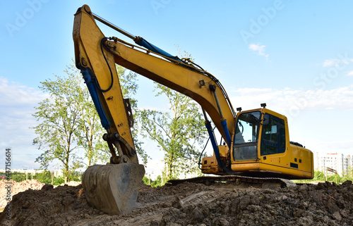 Excavator on earthworks at construction site. Backhoe on earthmoving and foundation work. Heavy machinery and equipment. Earth-moving heavy equipment on road works