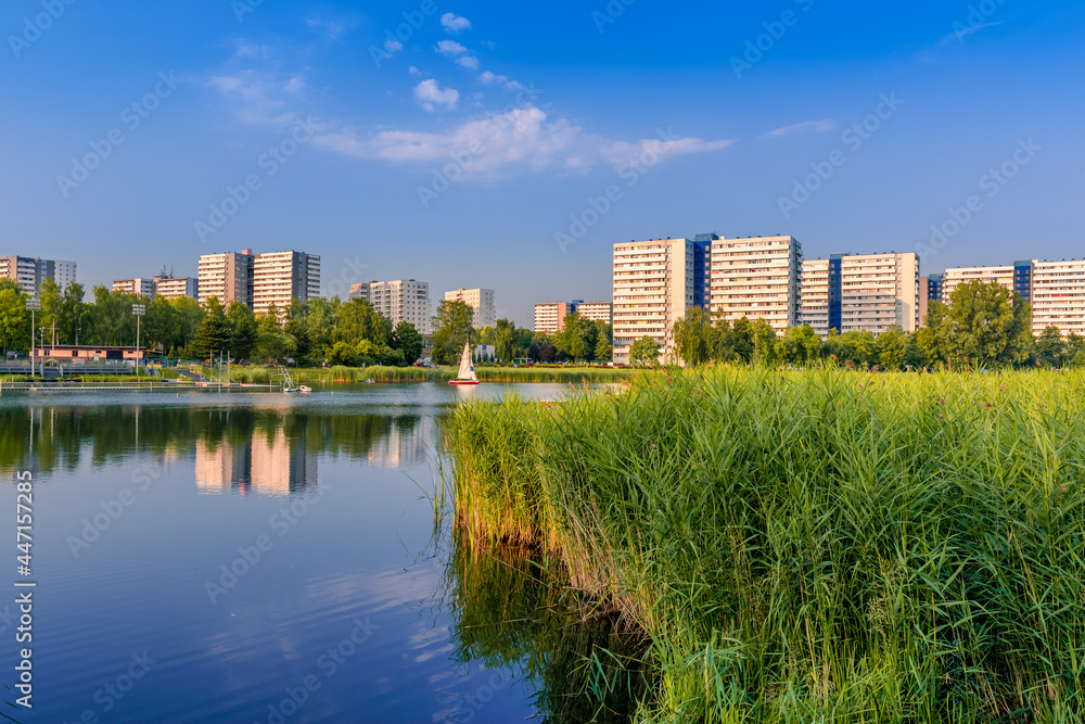 View at Tysiaclecie district in Katowice on a beautiful, sunny day, seen through the pond. Apartment buildings situated neat the lake against blue sky.