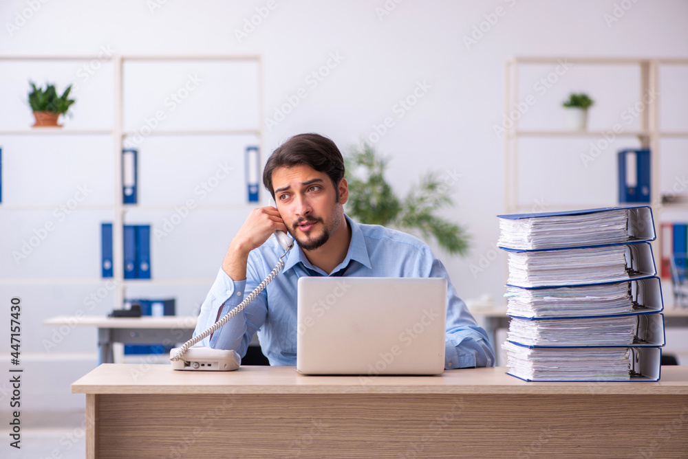 Young male employee and too much work in the office Young male employee and too much work in the office