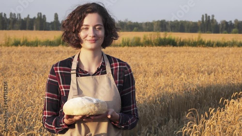 Wallpaper Mural A woman baker in a wheat field holds a loaf of white wheat bread in her hands and smiles. Healthy lifestyle concept, clean organic food, organic bread. Ears of golden wheat on the background
 Torontodigital.ca