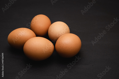 Five brown eggs on a black background
