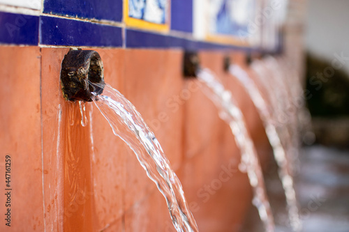ISTÁN, SPAIN: Flowing spring water at Fuente y Lavadero El Chorro, a tiled public fountain, historically used by residents for drinking water and washing clothes before the houses had flowing water