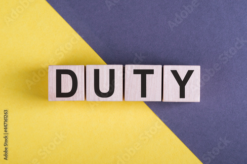 Word DUTY on wooden cubes on yellow - gray background.