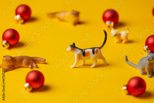 Canvas Print miniature cats figure next to red Christmas baubles on yellow background
