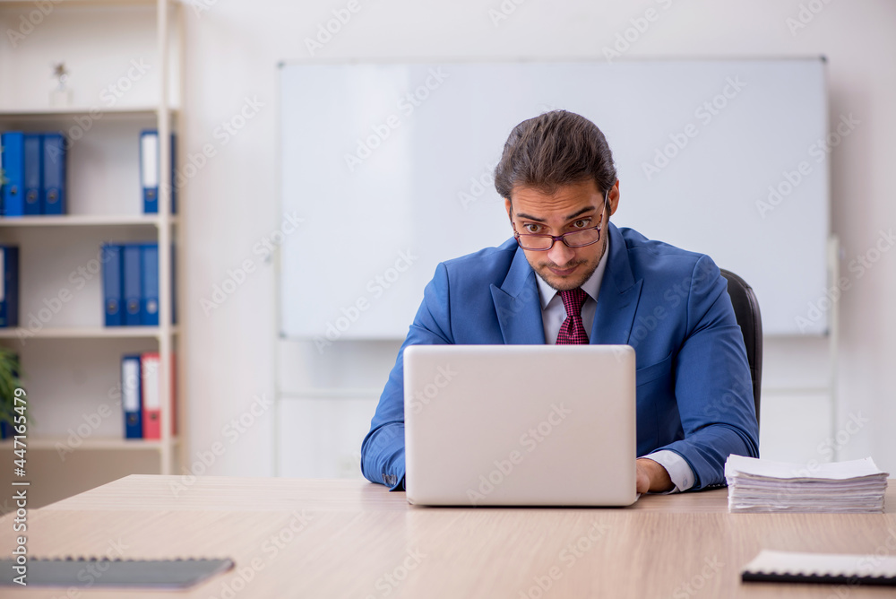 Young male employee sitting in the office in front of whiteboard Young male employee sitting in the office in front of whiteboard