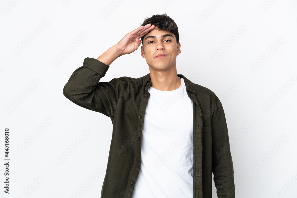 Young man over isolated white background saluting with hand with happy expression Young man over isolated white background saluting with hand with happy expression