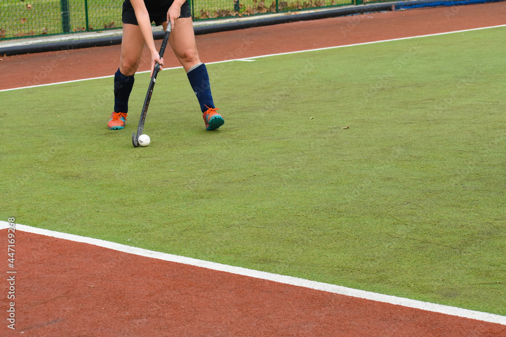 female hockey player running and passing the ball in a field