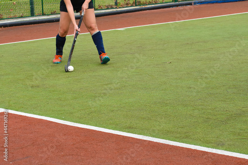 female hockey player running and passing the ball in a field