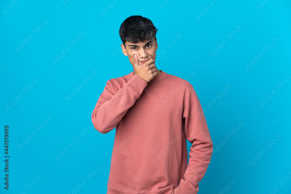 Young man over isolated blue background having doubts Young man over isolated blue background having doubts