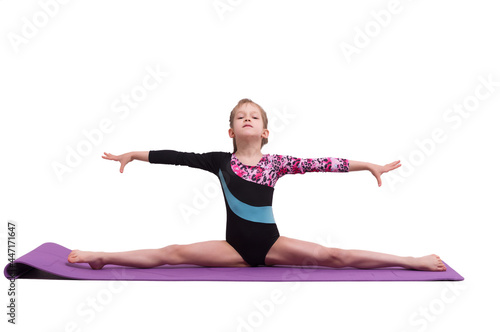 Foto Cute child girl making gymnastics exercises, doing split against white
