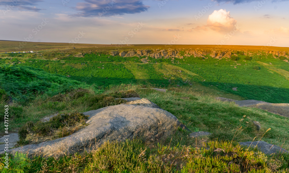 A Photograph of Stanage Edge Rocks and a View of a Far Rural Hill, at an English Countryside, During Sunset in Peak District, Sheffield, England.