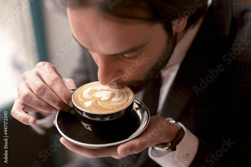 Young businessman appreciating his morning coffee with latte art drawing