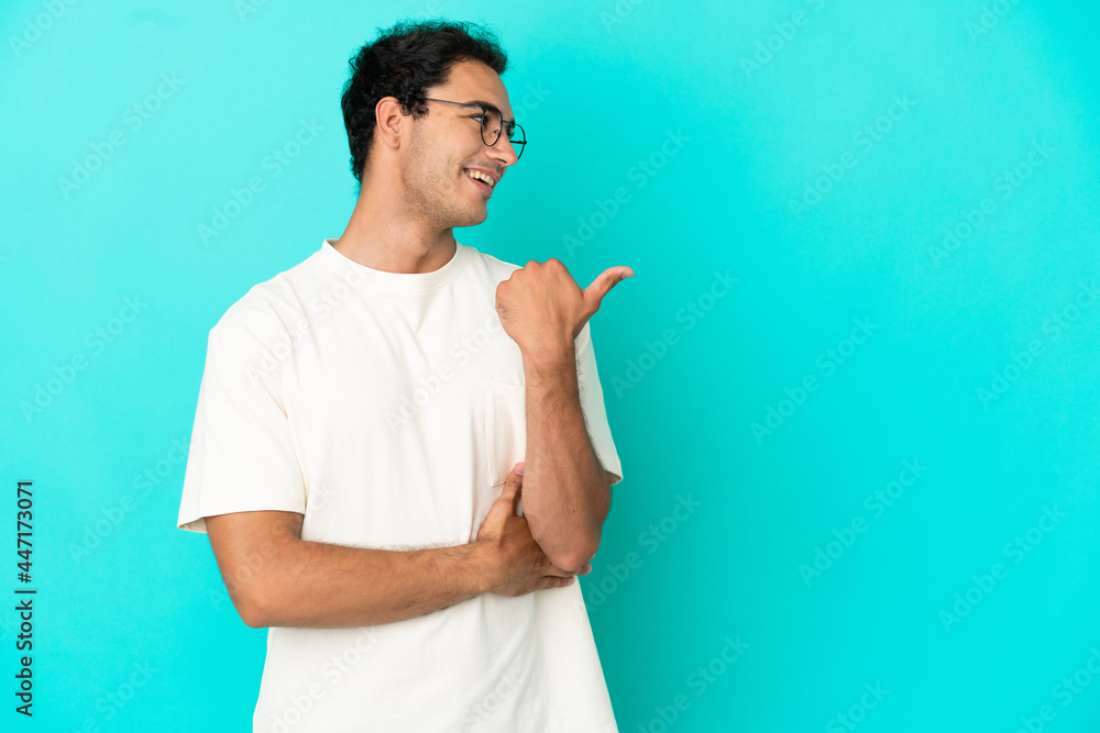 Caucasian handsome man over isolated blue background pointing to the side to present a product
