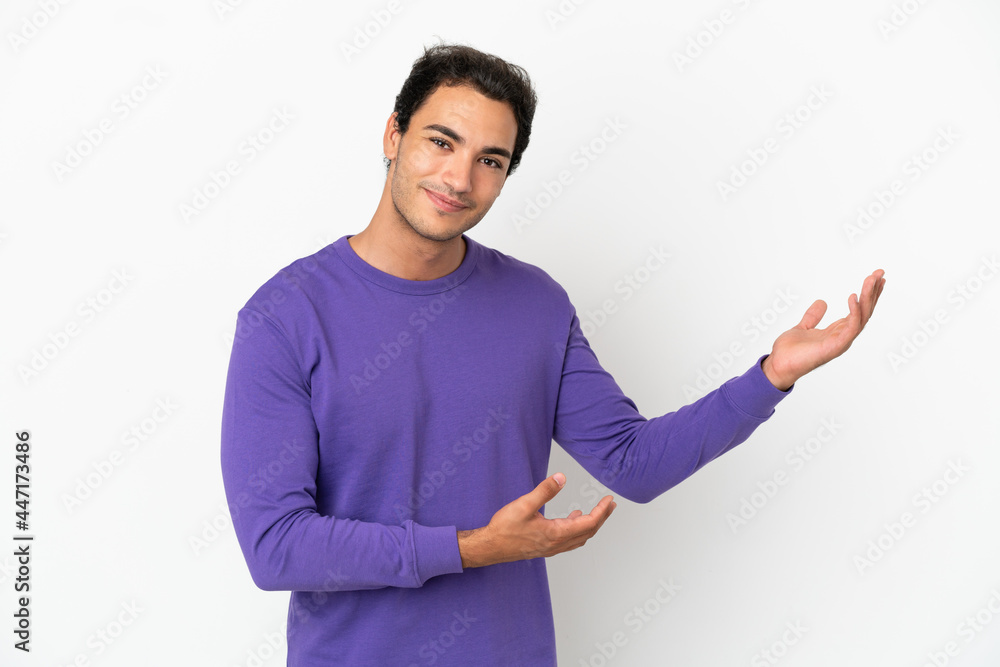 Caucasian handsome man over isolated white background extending hands to the side for inviting to come Caucasian handsome man over isolated white background extending hands to the side for inviting to come