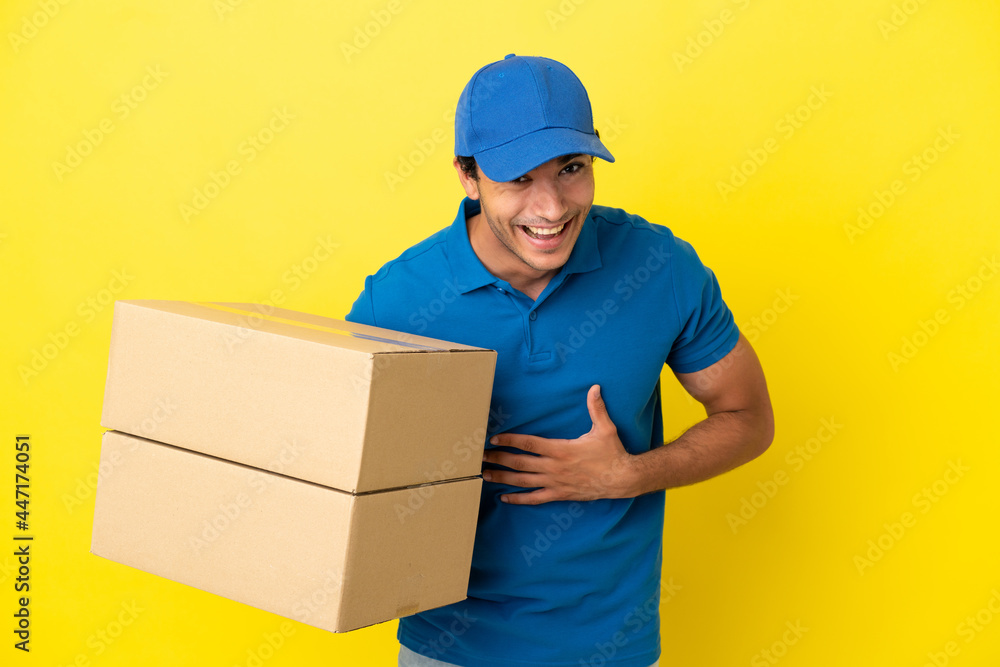 Delivery man over isolated yellow wall smiling a lot Delivery man over isolated yellow wall smiling a lot