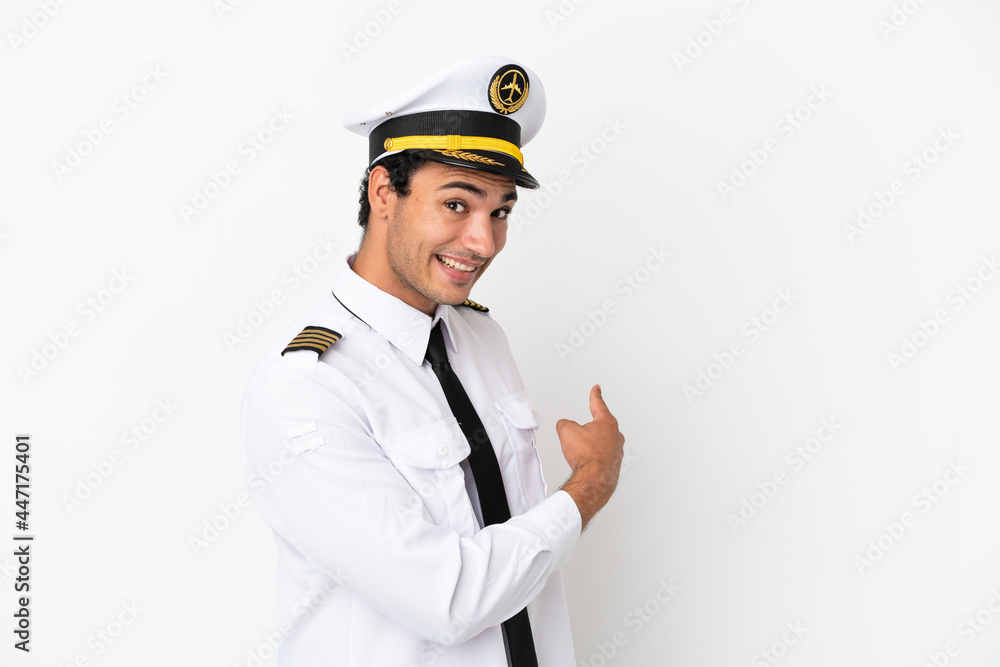 Airplane pilot over isolated white background pointing back Airplane pilot over isolated white background pointing back