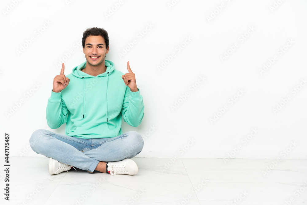Caucasian handsome man sitting on the floor pointing up a great idea