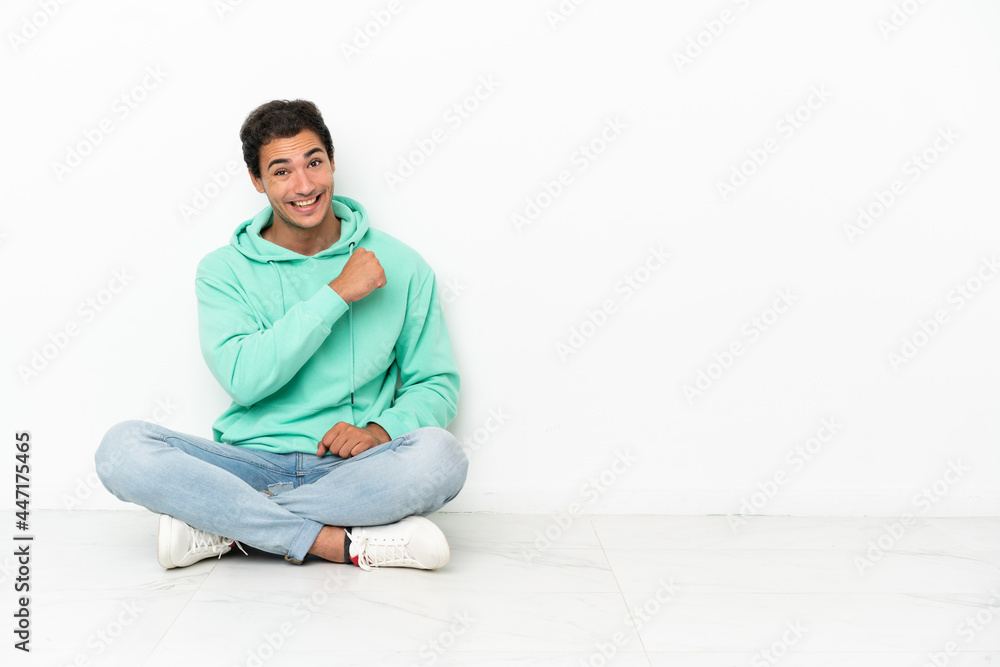 Caucasian handsome man sitting on the floor celebrating a victory Caucasian handsome man sitting on the floor celebrating a victory