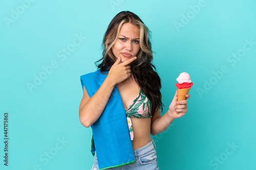 Teenager caucasian girl holding ice cream and towel isolated on blue background thinking