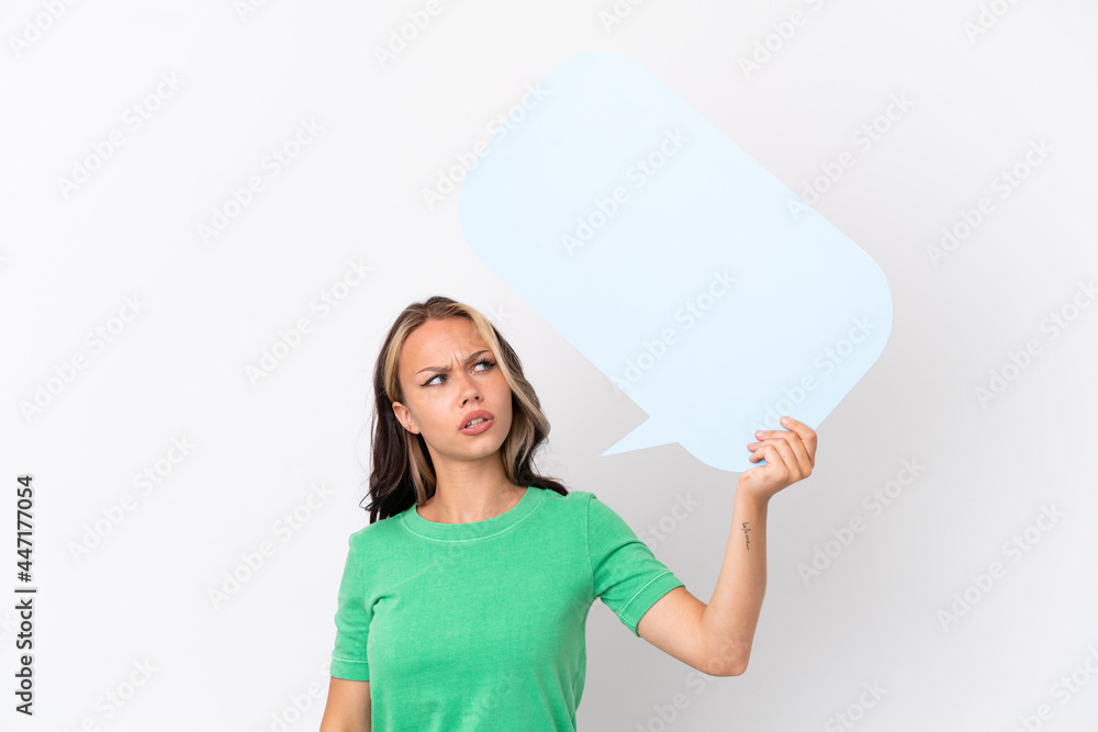 Teenager Russian girl isolated on blue background holding an empty speech bubble and with sad expression Teenager Russian girl isolated on blue background holding an empty speech bubble and with sad expression