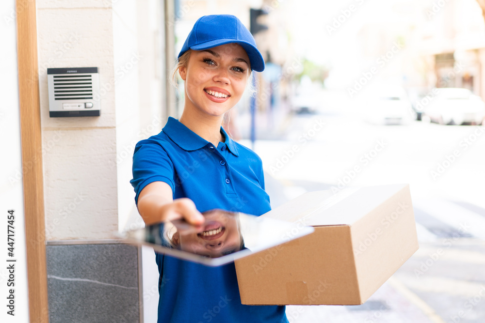 Young delivery woman at outdoors holding boxes and a tablet with happy expression Young delivery woman at outdoors holding boxes and a tablet with happy expression
