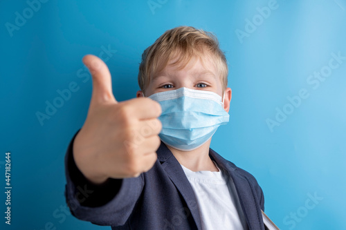 Portrait of school boy with face mask and school uniform. Blue background