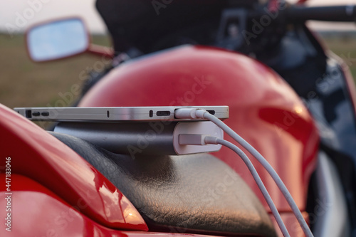 Smartphone on a motorcycle and Power Bank charges the phone against the backdrop of nature.